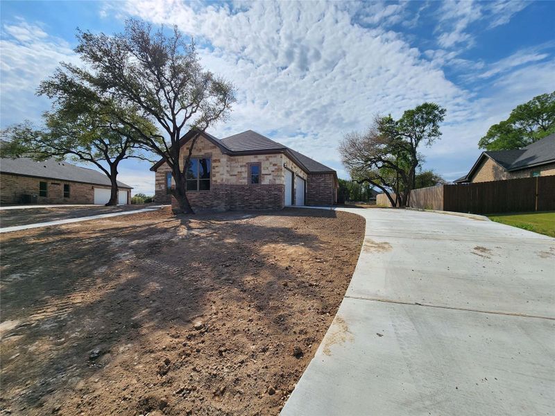 View of front of house with driveway, brick siding, and an attached garage