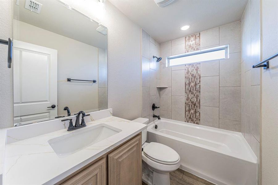 Bathroom featuring a white bathtub with tile surround, a built-in shower niche, and a transom window