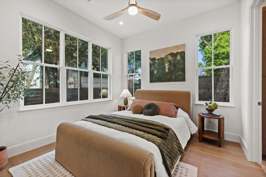 Hardwood floors and generous windows elevate this serene bedroom.