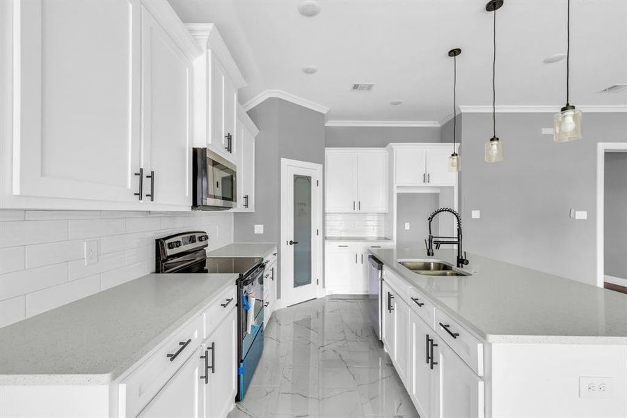 Kitchen with pendant lighting, a kitchen island with sink, appliances with stainless steel finishes, and white cabinets