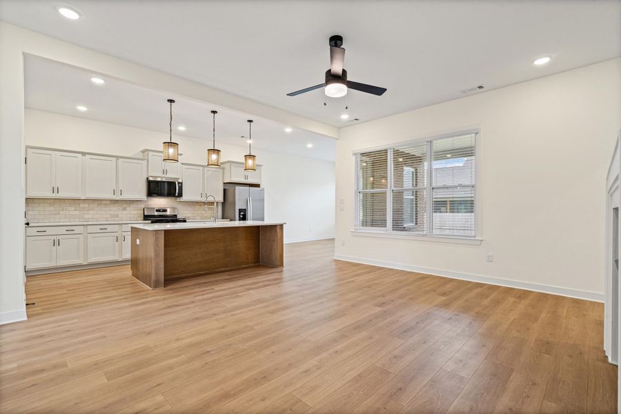 Open-concept living space featuring wood-finish flooring, recessed lighting, and a contemporary ceiling fan Open-concept living space featuring wood-finish flooring, recessed lighting, and a contemporary ceiling fan
