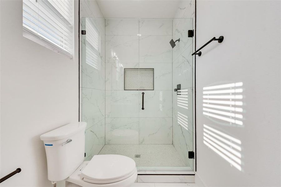 Bathroom featuring toilet and a shower with door