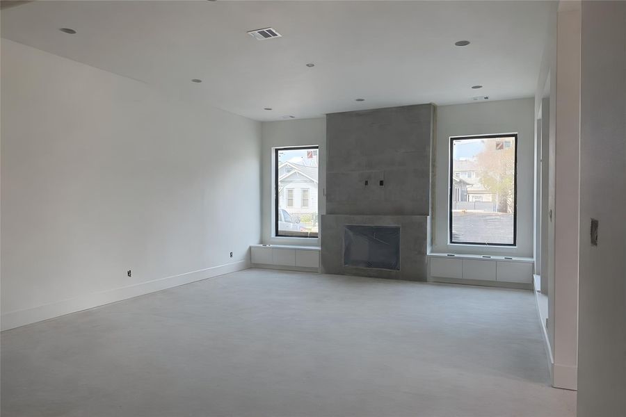 Living Room- Open-concept living area with soaring 11' ceilings and oversized black-framed windows. Flooring and finishes in progress. (Construction Photo as of 3/10/26 - Edited)