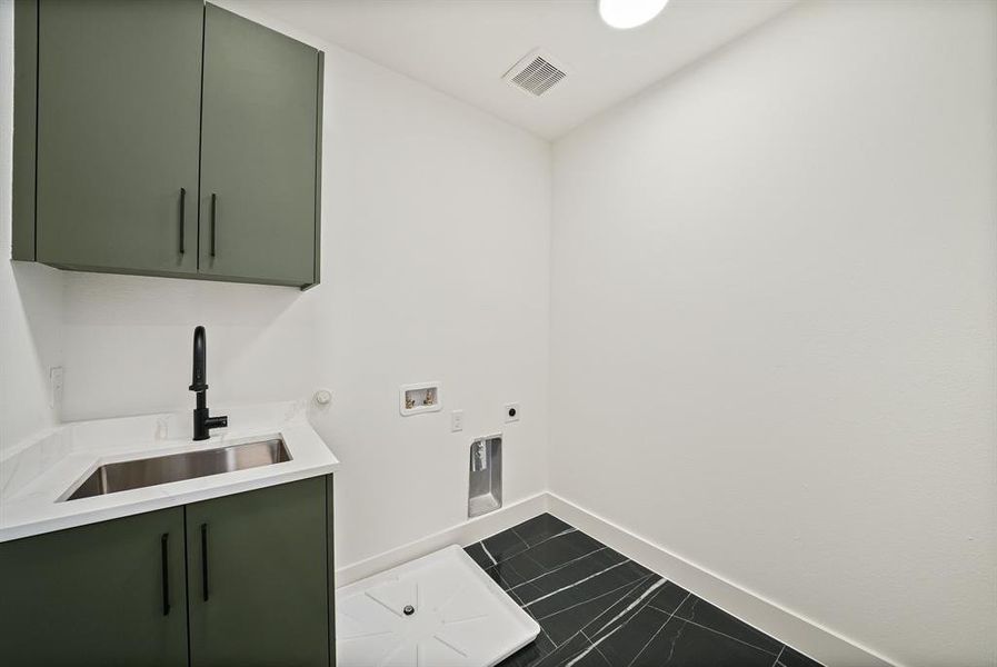 Dedicated laundry area featuring a utility sink, white countertop, and dark green cabinetry Dedicated laundry area featuring a utility sink, white countertop, and dark green cabinetry