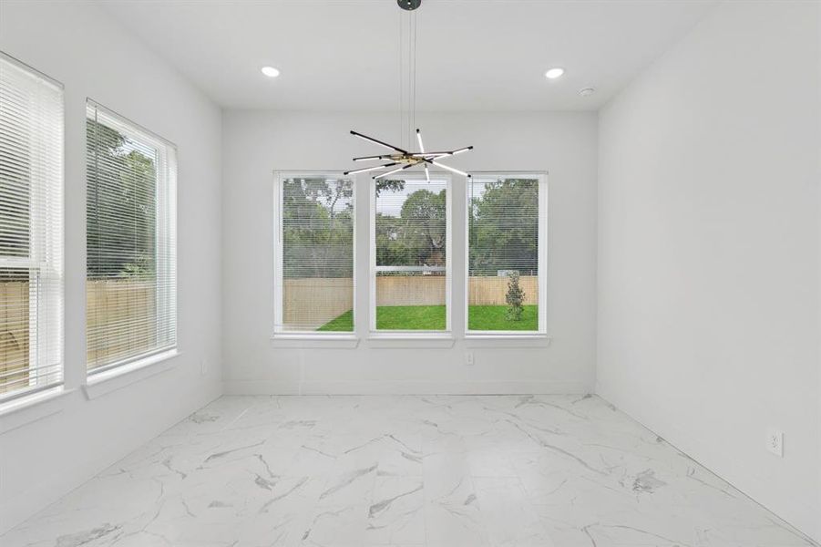 Unfurnished dining area featuring light marble finish flooring and recessed lighting