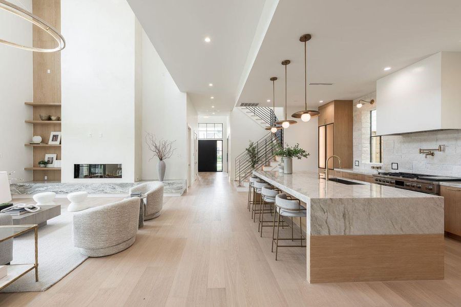 Bathed in natural light and grounded in organic tones, this culinary space balances clean-lined cabinetry with dramatic architectural elements. A seamless blend of form and function, the expansive prep island, custom vent hood, and curated open displays offer a backdrop equally suited for intimate dinners or lively gatherings.