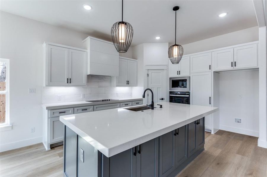 Kitchen featuring oven, black electric cooktop, a sink, white cabinetry, and built in microwave