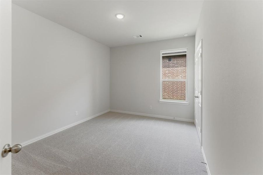 Spacious room featuring light gray carpeting, neutral wall paint, a single window with white trim, and a ceiling-mounted recessed light Spacious room featuring light gray carpeting, neutral wall paint, a single window with white trim, and a ceiling-mounted recessed light