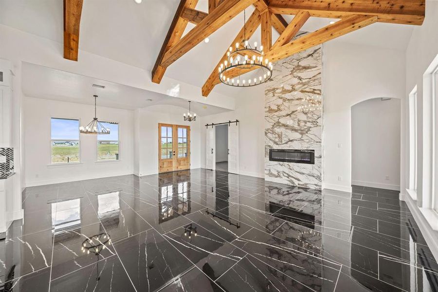 Living area featuring high vaulted ceiling, a chandelier, plenty of natural light, french doors, and baseboards Living area featuring high vaulted ceiling, a chandelier, plenty of natural light, french doors, and baseboards