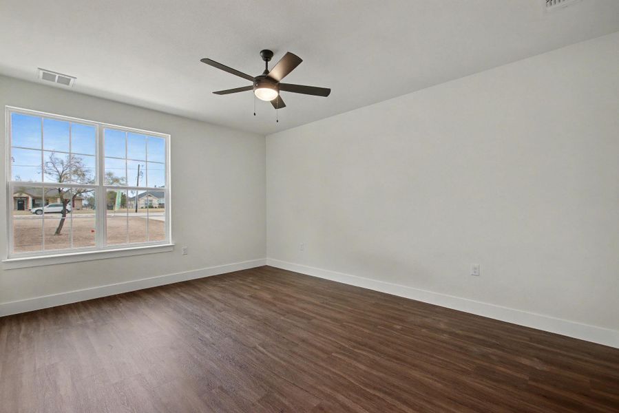 Empty room featuring dark wood-type flooring and a ceiling fan