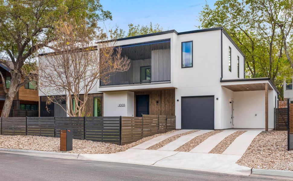 Contemporary home with a fenced front yard, stucco siding, a balcony and a front porch