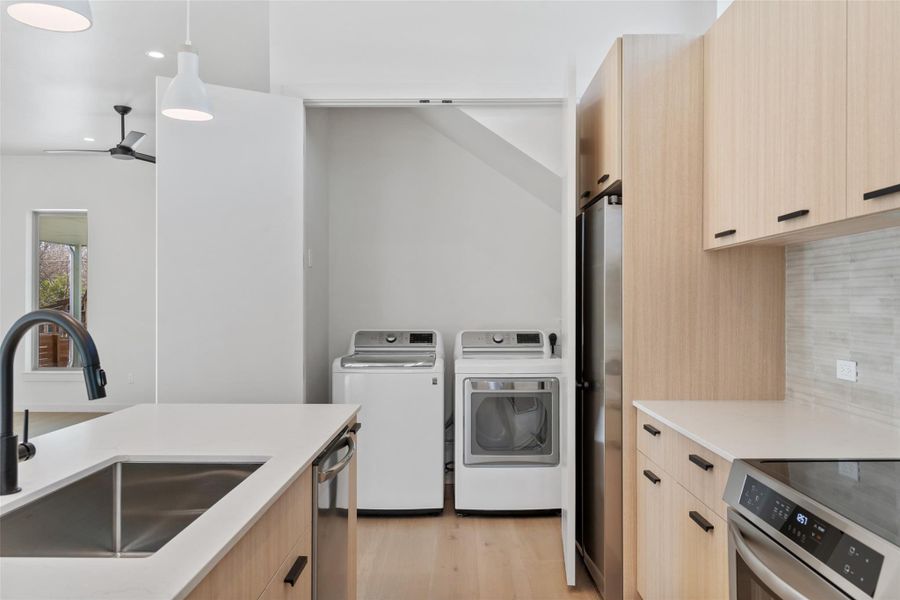 Kitchen featuring a sink, light brown cabinetry, modern cabinets, and washing machine and dryer