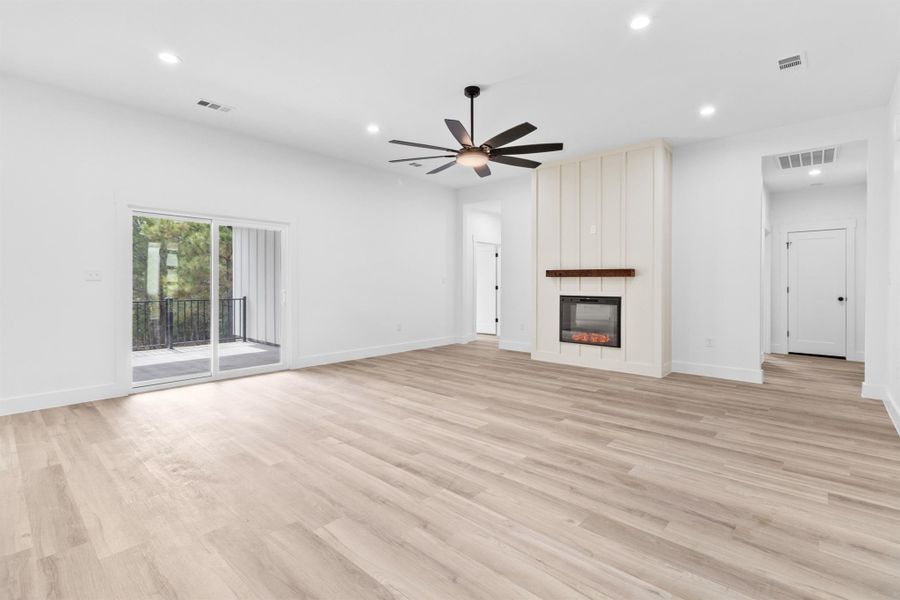 Unfurnished living room featuring recessed lighting, light wood-style flooring, a large fireplace, and a ceiling fan