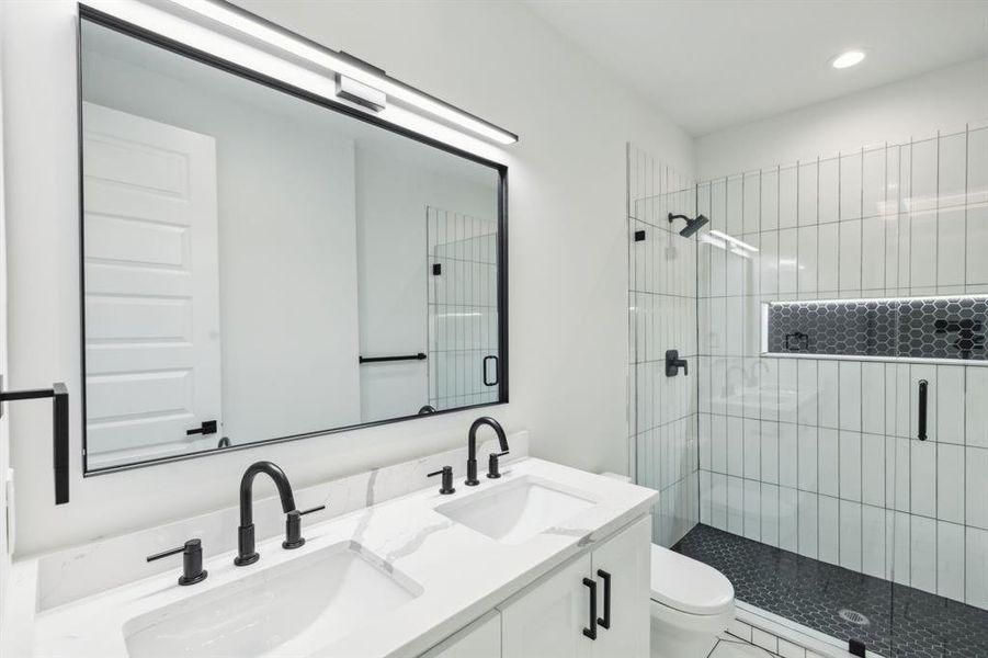 Bathroom featuring a shower with shower door, vanity, and toilet