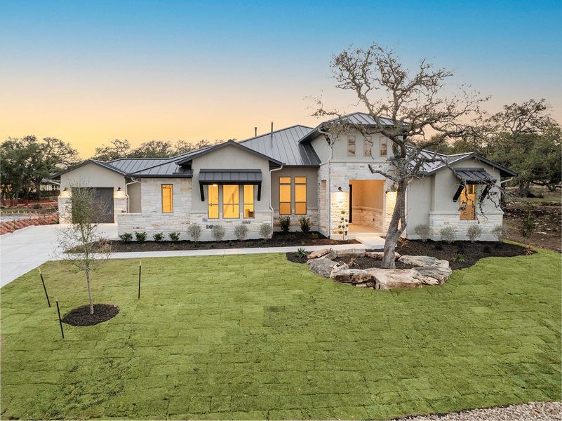 View of front of home featuring stone siding, metal roof, a standing seam roof, and a front yard View of front of home featuring stone siding, metal roof, a standing seam roof, and a front yard