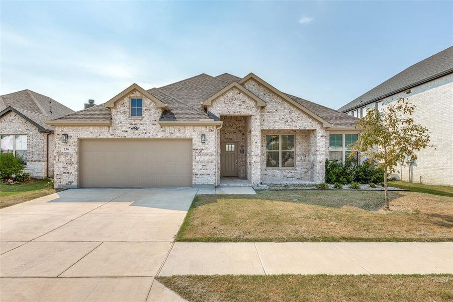 French country home with a shingled roof, a front lawn, brick siding, driveway, and an attached garage French country home with a shingled roof, a front lawn, brick siding, driveway, and an attached garage