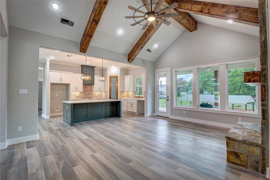 Unfurnished living room featuring ceiling fan, light hardwood / wood-style flooring, a healthy amount of sunlight, and beam ceiling Unfurnished living room featuring ceiling fan, light hardwood / wood-style flooring, a healthy amount of sunlight, and beam ceiling