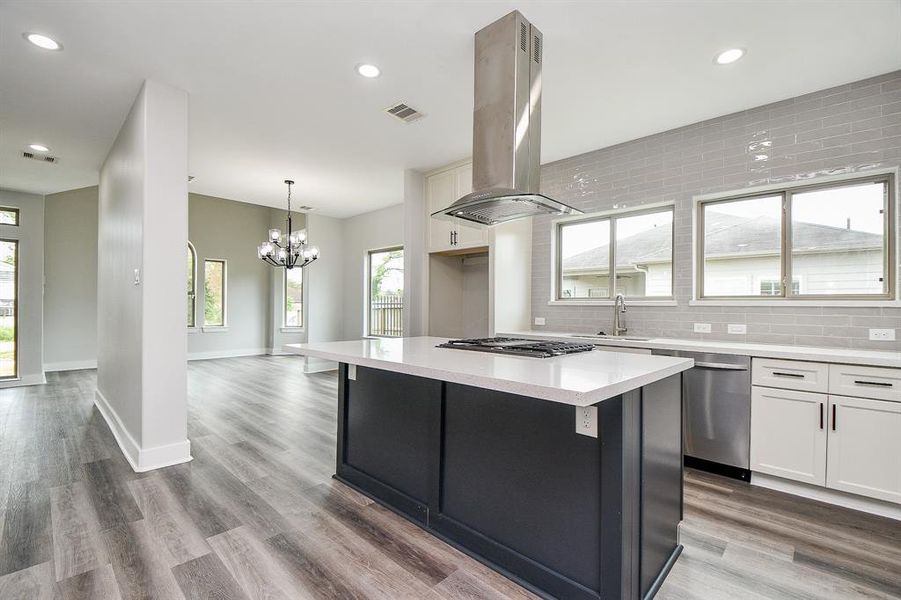 Modern open-concept kitchen with a large island, stainless steel appliances, and sleek cabinetry, leading into a spacious living area with contemporary lighting and ample natural light.