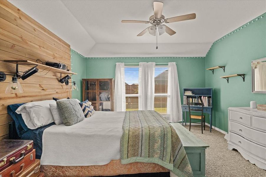 Carpeted bedroom featuring ceiling fan, wood walls, and lofted ceiling