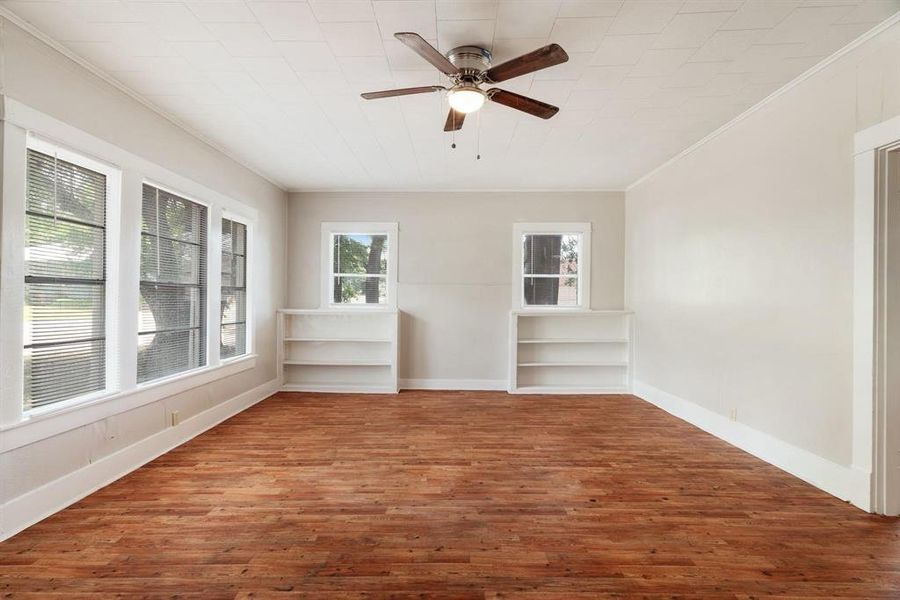 Empty room with ornamental molding, wood finished floors, and a ceiling fan Empty room with ornamental molding, wood finished floors, and a ceiling fan