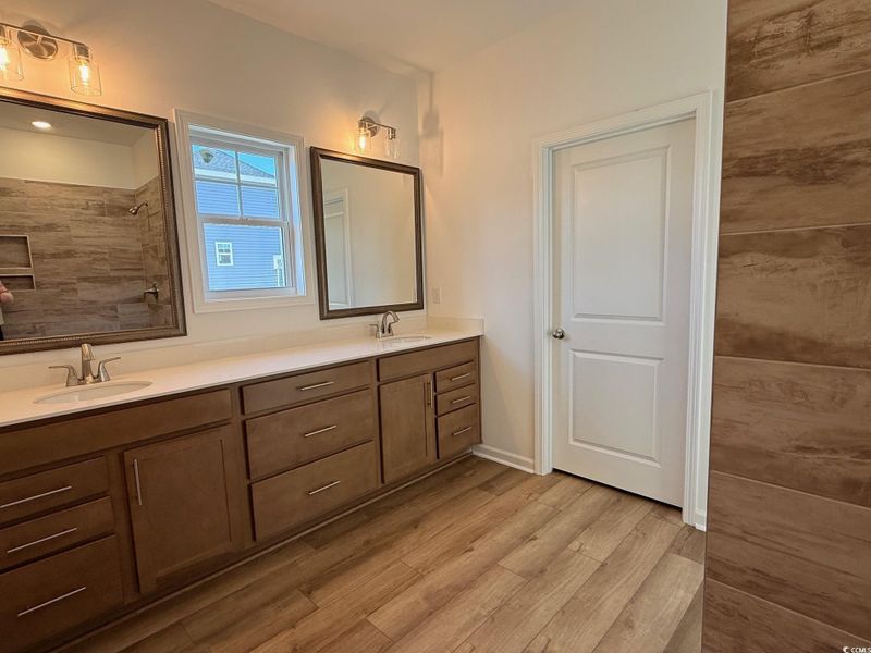 Full bathroom with double vanity, framed mirrors & light  and tile shower.