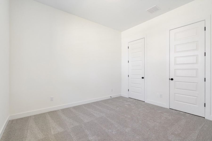 Neutral-toned carpeting, five-panel interior doors, and matte black door hardware Neutral-toned carpeting, five-panel interior doors, and matte black door hardware