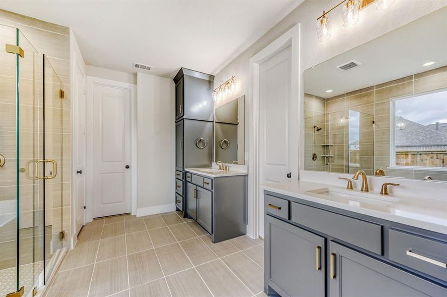 Full bath featuring a shower stall, two vanities, and light tile patterned floors