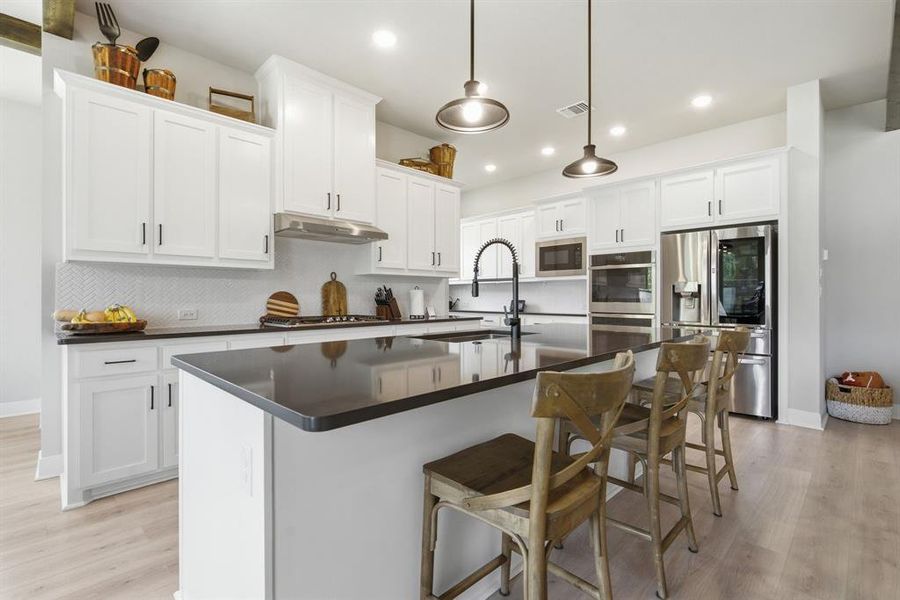 The Inviting Island Kitchen Features Abundant Cabinets And Quartz Countertops, Tile Backsplash, Stainless Appliances, Breakfast Bar And Ample Lighting.