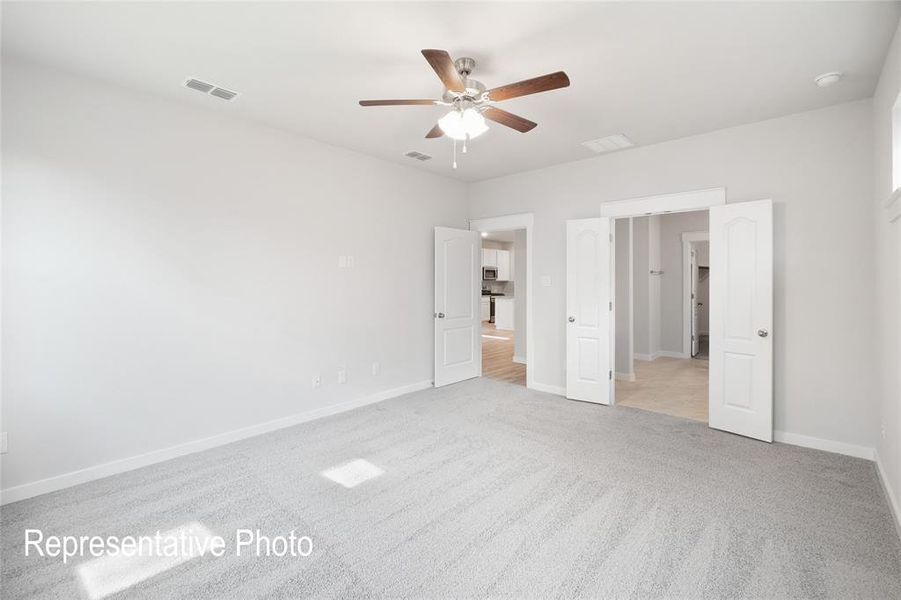 Spacious room featuring light gray carpet, white walls, and a ceiling fan with wooden blades