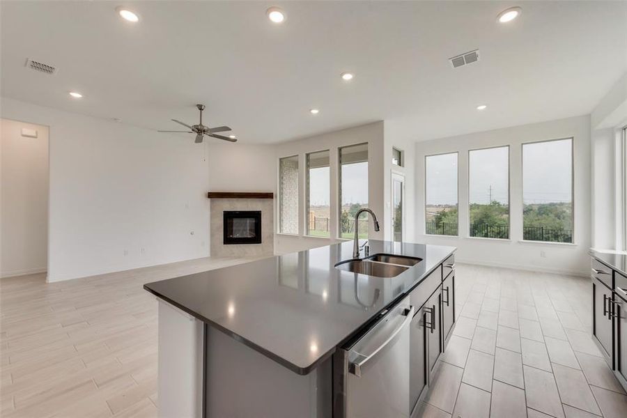 Kitchen featuring ceiling fan, sink, a kitchen island with sink, dishwasher, and light wood-type flooring