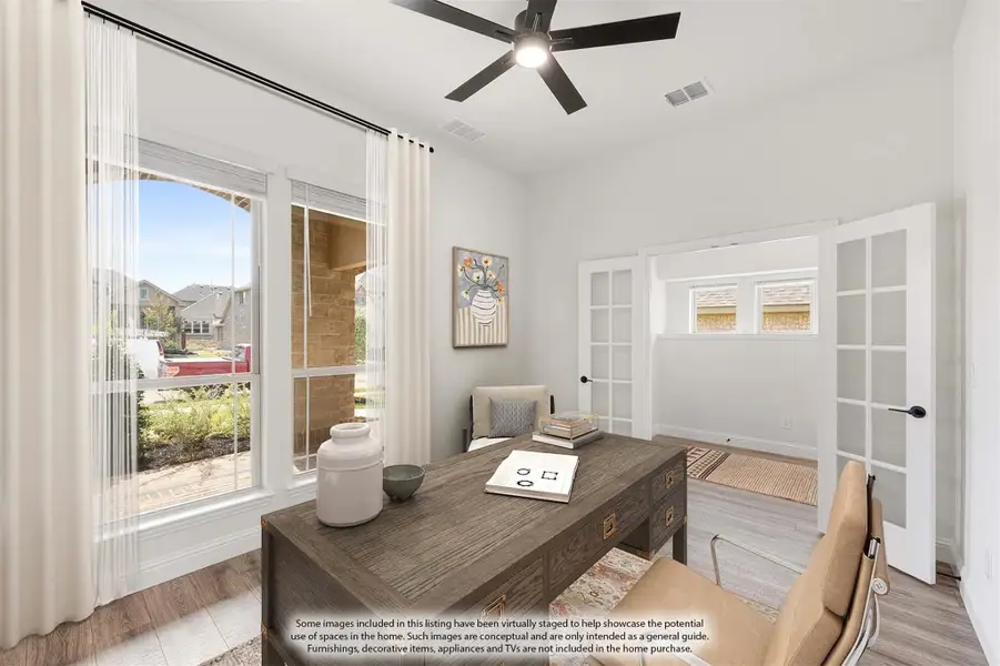 Home office with wood desk, ceiling fan, French doors, and large windows with natural light