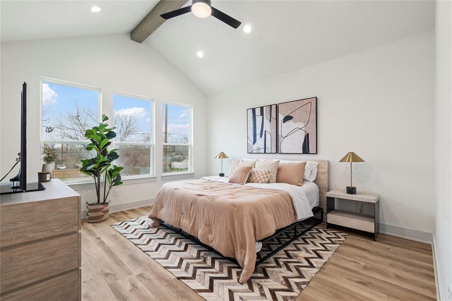 A luxurious primary suite with soaring cathedral ceilings, oversized windows that bathe the room in natural light, and wide plank luxury LVP floors.