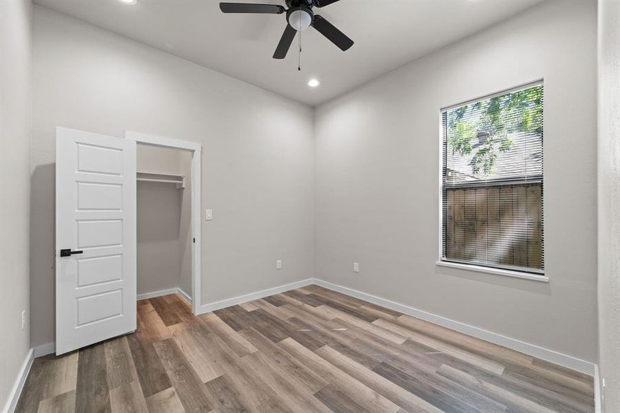 Unfurnished bedroom with ceiling fan, a closet, wood-type flooring, and a walk in closet