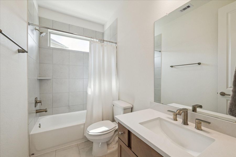 A first-floor full bathroom, conveniently located adjacent to the primary suite, is perfect for guests and features a shower/tub combo with modern finishes.