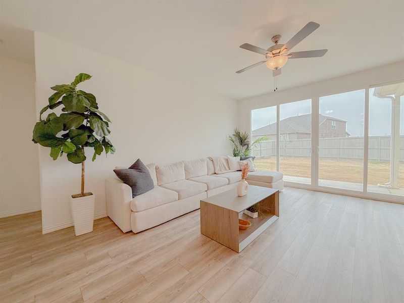 Living area with ceiling fan, light wood-style flooring, and baseboards