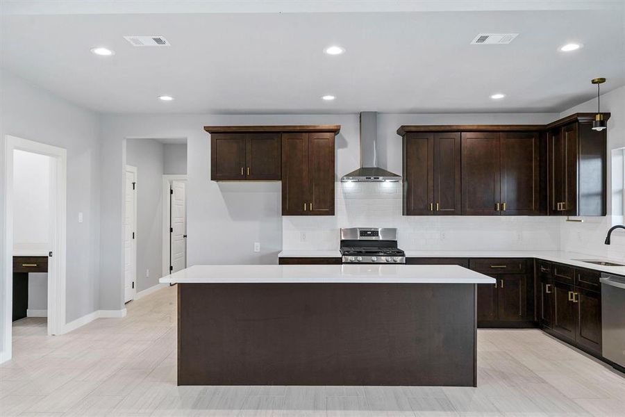 Kitchen featuring sink, a center island, wall chimney exhaust hood, and appliances with stainless steel finishes