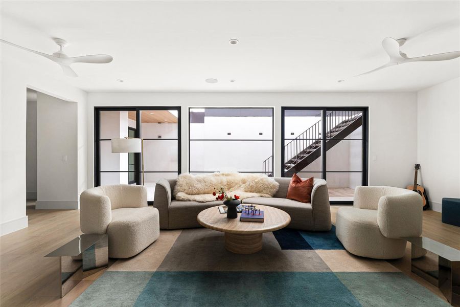 Living room with a ceiling fan, light wood-style flooring, and plenty of natural light