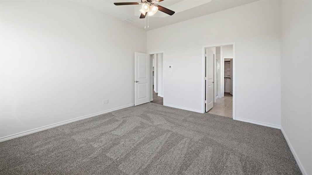 Carpeted interior room with white walls, baseboards, and a ceiling fan