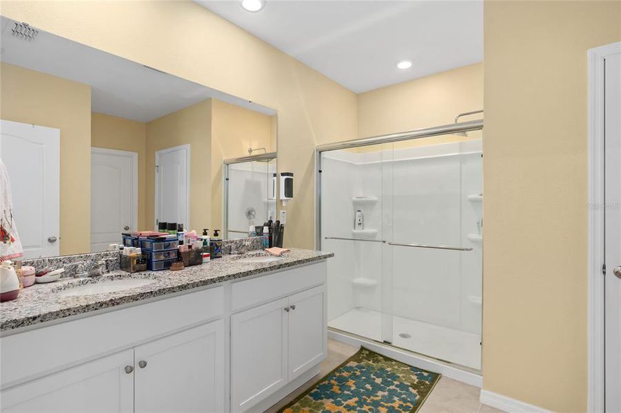 primary bathroom, beautiful cabinetry with granite countertop, dual undermount sinks with walk in shower and custom shower door