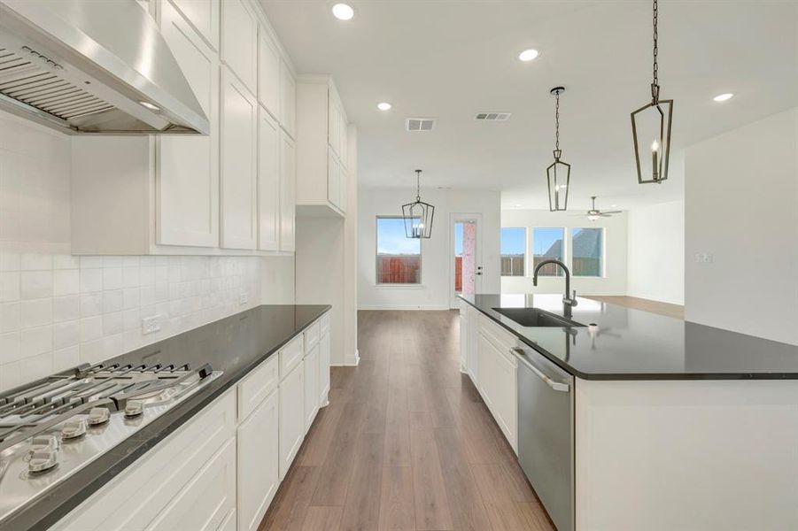 Kitchen featuring white cabinetry, stainless steel appliances, dark wood-type flooring, hanging light fixtures, and a spacious island Kitchen featuring white cabinetry, stainless steel appliances, dark wood-type flooring, hanging light fixtures, and a spacious island