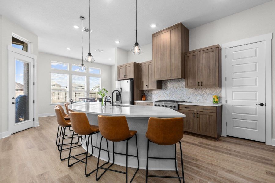 Kitchen featuring a breakfast bar area, light wood-style flooring, a deep sink, stylish tiled backsplash, and a large center island