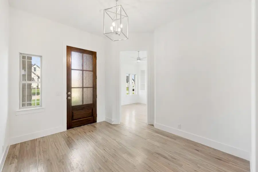 Bright entryway with wood front door, geometric pendant light, and light hardwood floors Bright entryway with wood front door, geometric pendant light, and light hardwood floors