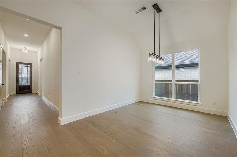 Unfurnished dining area featuring light wood-style floors and vaulted ceiling