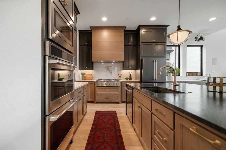 Kitchen featuring stainless steel appliances, backsplash, recessed lighting, pendant lighting, and light wood-style floors Kitchen featuring stainless steel appliances, backsplash, recessed lighting, pendant lighting, and light wood-style floors