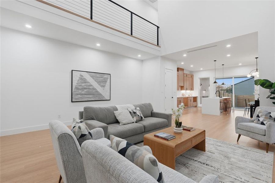 Living room with a high ceiling, light wood-style floors, and recessed lighting