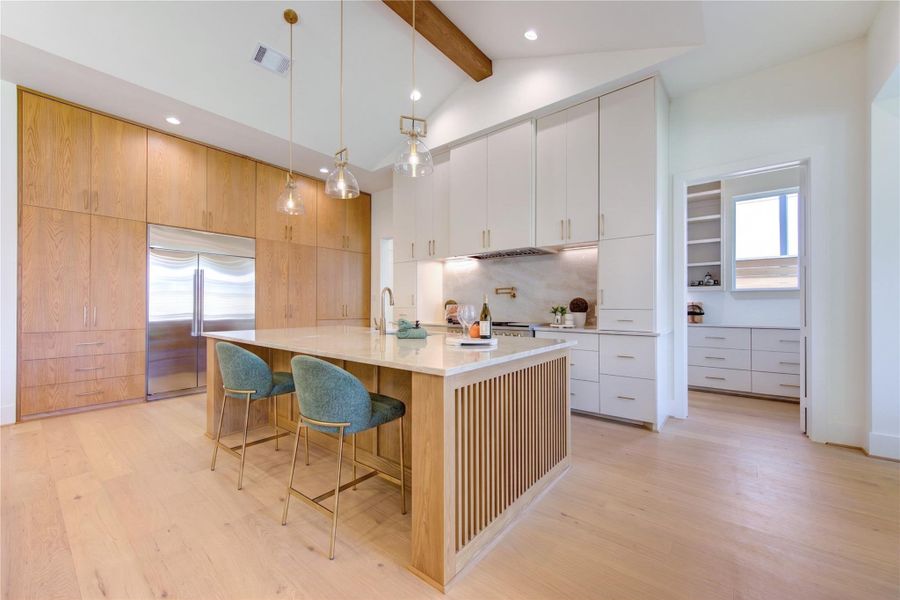 The chef-inspired kitchen is a masterclass in both design and functionality, anchored by an oversized quartzite island with custom fluted wood detailing that serves as a natural gathering space for family and guests. Floor-to-ceiling custom cabinetry provides abundant storage while showcasing warm wood accents paired with sleek painted finishes for a timeless, sophisticated aesthetic.