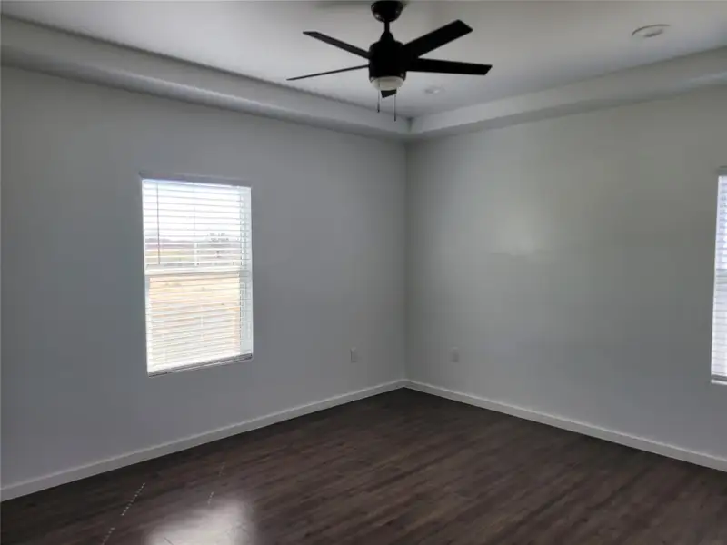 Empty room featuring dark wood-style flooring and ceiling fan