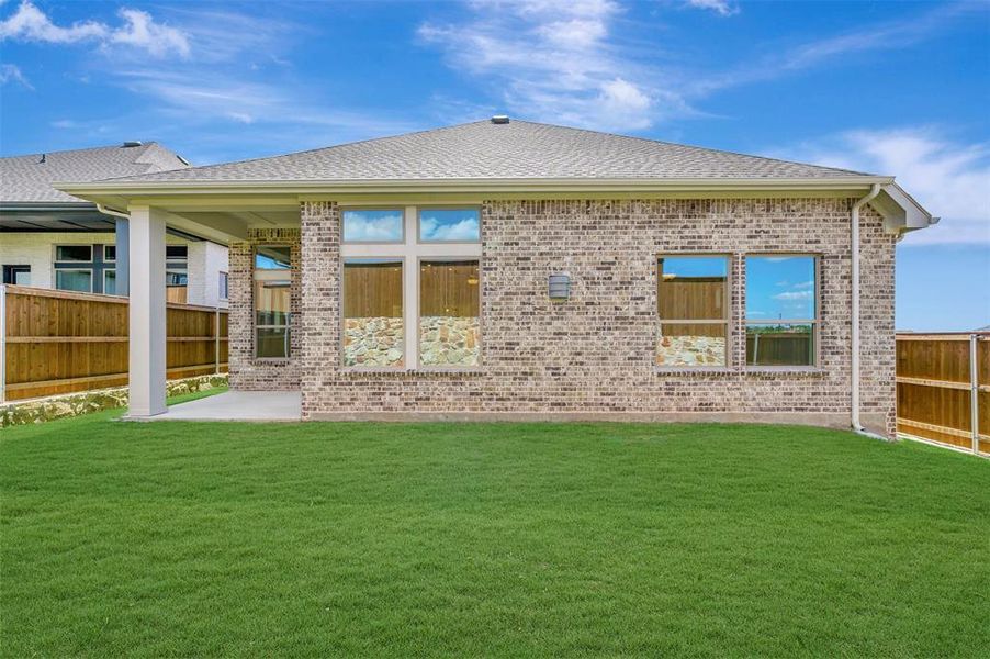 Expansive green lawn with a brick exterior, covered patio, and privacy fencing Expansive green lawn with a brick exterior, covered patio, and privacy fencing