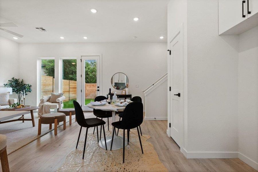 Open concept living and dining area featuring light-colored flooring, recessed lighting, and access to the outdoors through glass doors