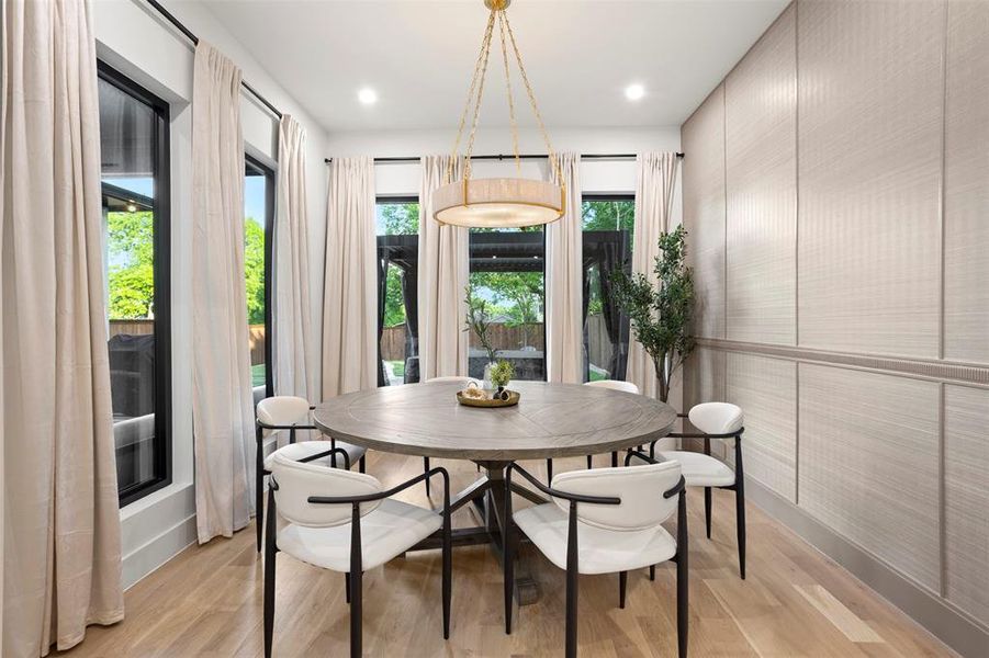 Dining space featuring wood-finish flooring, a contemporary chandelier, and a paneled accent wall